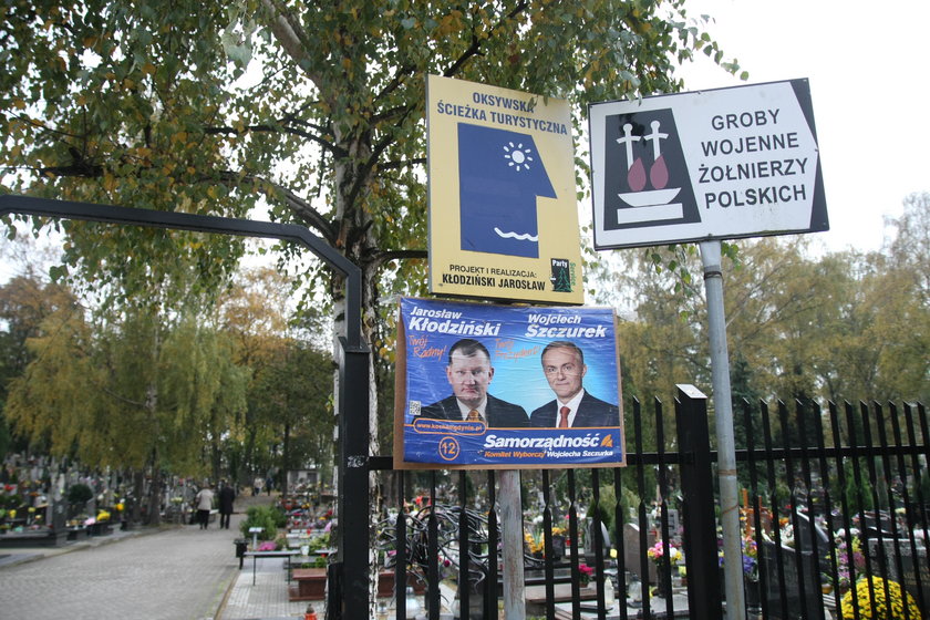 Plakat wyborczy prezydenta Wojciecha Szczurka wisi na cmentarnym ogrodzeniu