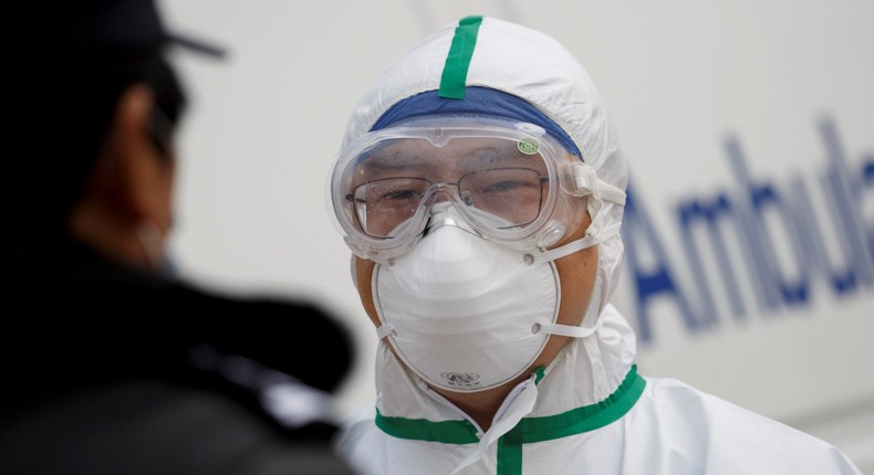 A hospital staff member in protective garments talks to a police officer at a checkpoint to the Hubei province exclusion zone at the Jiujiang Yangtze River Bridge in Jiujiang