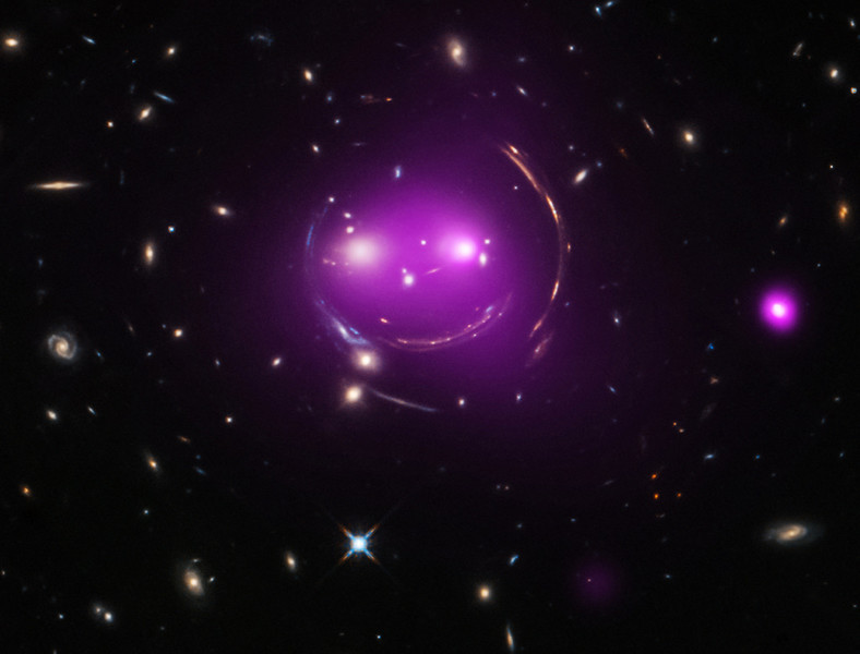 Kosmiczny uśmiech grupy galaktyk, znanej jako Kot z Cheshire. Ogólna teoria względności przewiduje zjawisko soczewkowania grawitacyjnego. To właśnie ono nadaje tym odległym galaktykom niecodzienny wygląd. Dwie duże galaktyki eliptyczne ("oczy" kota) pędzą ku sobie z prędkością ponad 483 tys. km na godzinę. Reprezentują najjaśniejsze galaktyki należące do grupy galaktyk pierwszego planu, czyli soczewkującego rozkładu masy grawitacyjnej. Otaczają je łuki – to obrazy dużo dalszych galaktyk tła. Masa soczewki grawitacyjnej jest zdominowana przez ciemną materię. Fioletowa poświata rentgenowska grupy widocznej na pierwszym planie została zarejestrowana przez teleskop orbitalny Chandra. Optyczne obrazy galaktyk wykonał Kosmiczny Teleskop Hubble'a. Kot z Cheshire uśmiecha się do nas z gwiazdozbioru Wielkiej Niedźwiedzicy, z odległości 4,6 miliarda lat świetlnych.