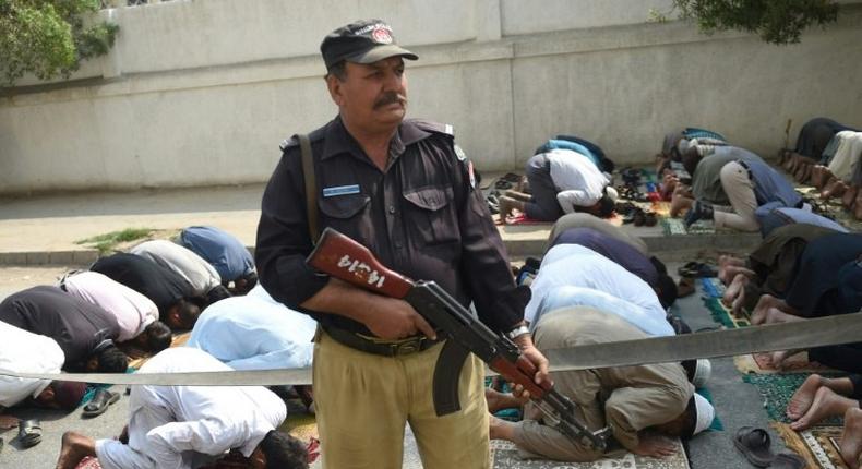 A Pakistani policeman stands guard as Muslims offer Friday prayers on a street in Karachi, on February 17, 2017