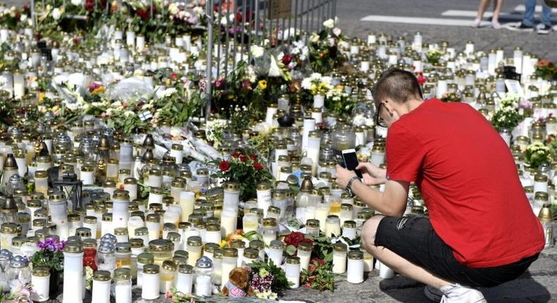 People bring candles and flowers to a makeshift memorial for the victims of the stabbings in the Finnish city of Turku