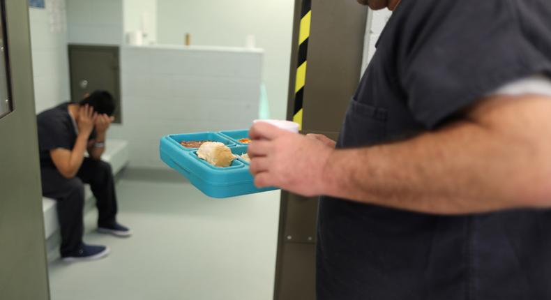 An immigrant takes food into a cell for incoming ICE detainees at the Adelanto immigration detention center, which is run by the Geo Group Inc (GEO.N), in Adelanto, California.