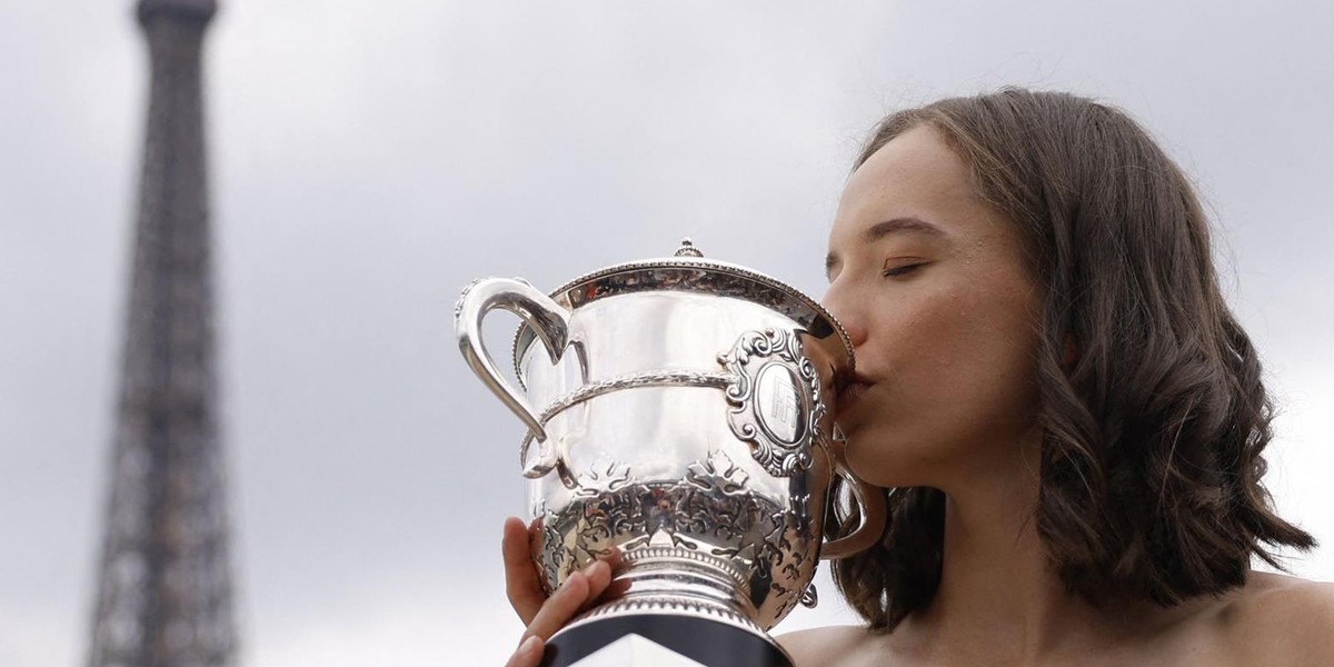 Na tle Wieży Eiffla Iga "w czerni" całuje puchar Suzanne Lenglen.