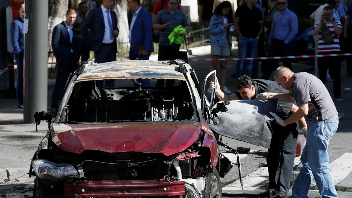 Investigators inspect a damaged car at site where journalist Pavel Sheremet was killed by a car bomb