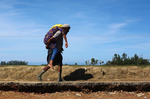 A Rohingya refugee man carries a woman after crossing the Bangladesh-Myanmar border by boat through 