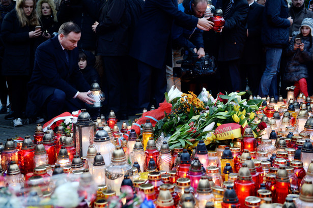 Prezydent Andrzej Duda zapala znicz przed Ambasadą Republiki Francuskiej w Warszawie