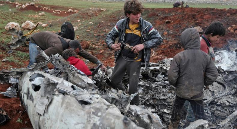 Syrians inspect the wreckage of a regime military helicopter after it was brought down over western Aleppo province