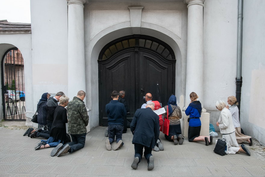 Ks. Michał Woźnicki razem z wyznawcami modli się przed zamkniętymi drzwiami kościoła, do którego salezjanie zakazali mu wstępu. 