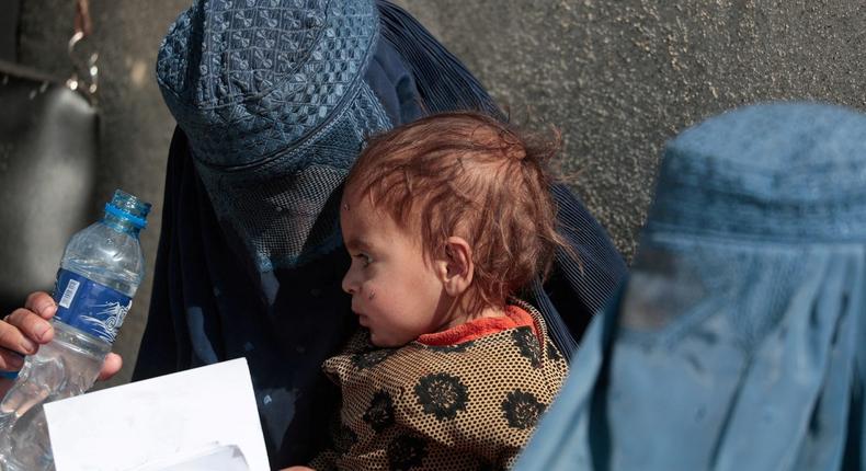 A displaced Afghan woman holds her child as she waits outside a UNCHR distribution center outside Kabul.