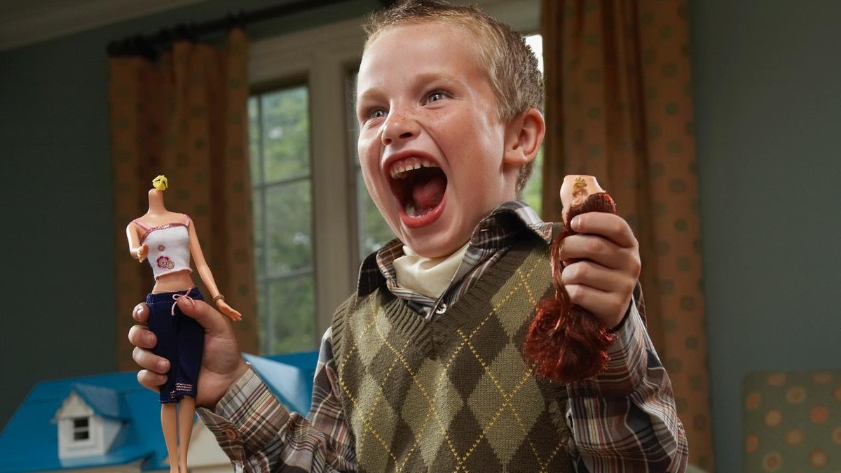 Boy (6-7 years) holding decapitated dolls and yelling