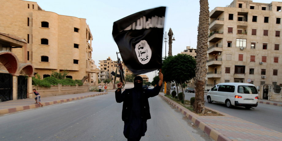 A member loyal to ISIS waves an ISIS flag in Raqqa on June 29, 2014.
