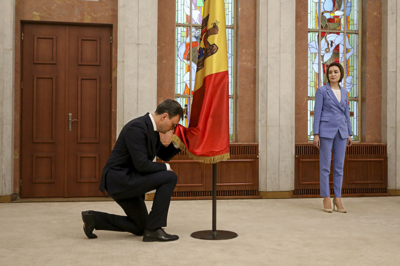 Prezydent Mołdawii Maia Sandu (z prawej) patrzy, jak premier Mołdawii Dorin Recean klęka przed flagą narodową podczas ceremonii zaprzysiężenia w Kiszyniowie, Mołdawia, czwartek, 16 lutego 2023 r.