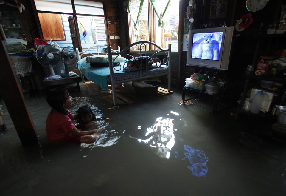 Residents watch television at their flooded house in Bangkok