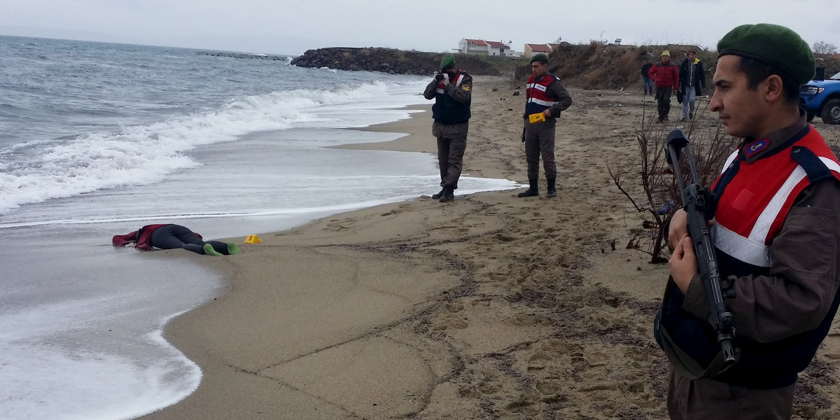 A Turkish gendarme forensic officer takes pictures as the body of a migrant lies on the shore in the Aegean coastal town of Dikili, near the western city of Izmir, Turkey