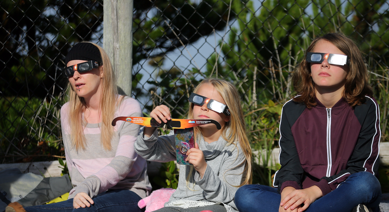 People use solar viewing glasses as the sun emerges through fog cover before the solar eclipse in Depoe Bay, Oregon, U.S., August 21, 2017.