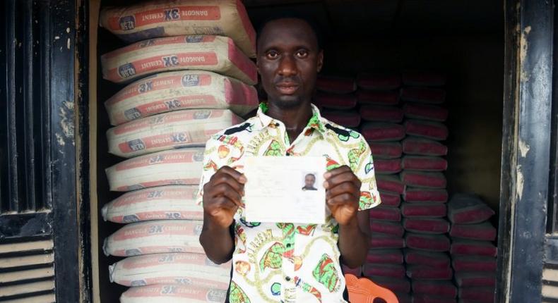 Mike Esorae displays document that denied his stay in France at his cement shop, Idogbo village, in midwest Nigeria, on October 21, 2016