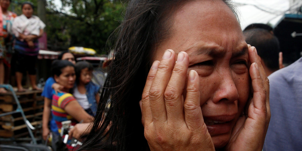 A family friend weeps after Nora Acielo, 47, was gunned down by unidentified men while escorting her two children to school in Manila