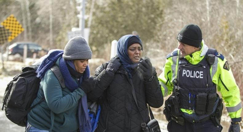 An RCMP officer speaks with women from Sudan after they illegally crossed the Canada-US border near Hemmingford, Quebec