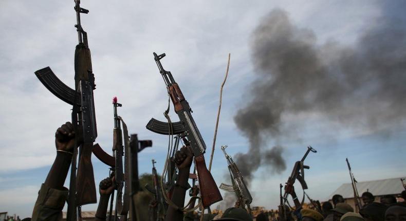 Rebel fighters hold up their rifles as they walk in front of a bushfire in a rebel-controlled territory in Upper Nile State, South Sudan February 13, 2014. REUTERS/Goran Tomasevic