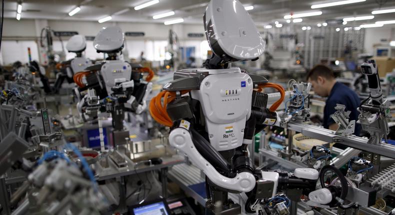 Humanoid robots work side by side with employees in the assembly line at a factory of Glory Ltd., a manufacturer of automatic change dispensers, in Kazo, north of Tokyo, Japan, July 1, 2015.