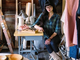 Mixed race seamstress sitting at sewing machine in studio