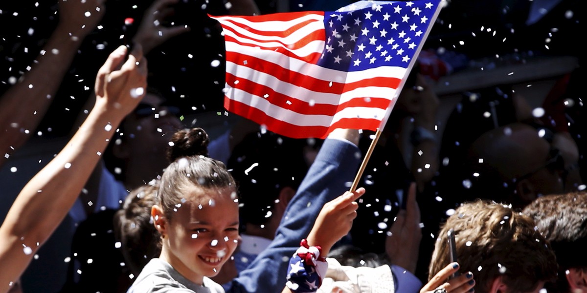 A fan holds an American flag as paper falls from buildings above during the ticker tape parade for the U.S. women's soccer team to celebrate their World Cup final win over Japan, in New York, July 10, 2015.