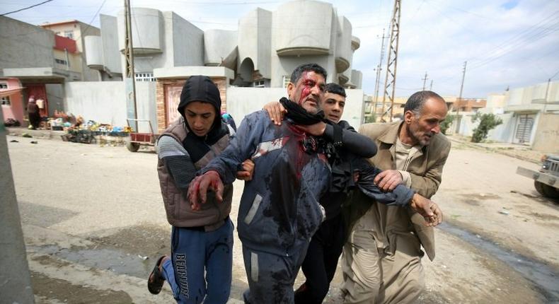 Iraqi civilians help a man who was injured by a mortar shell fired by Islamic State group jihadists on civilians who were gathered to receive aid, in Al-Risala neighbourhood on March 22, 2017