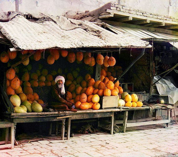Sprzedawca melonów ubrany w tradycyjny strój z Azji Środkowej, sprzedający towar na rynku Samarkandy w dzisiejszym Uzbekistanie (między 1905 a 1915, domena publiczna).