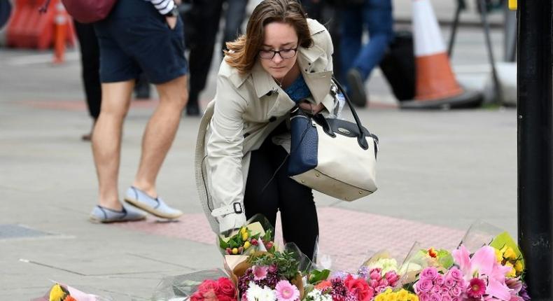 A woman lays a bouquet of flowers at a pedestrian crossing by Borough market following attacks which left eight people dead