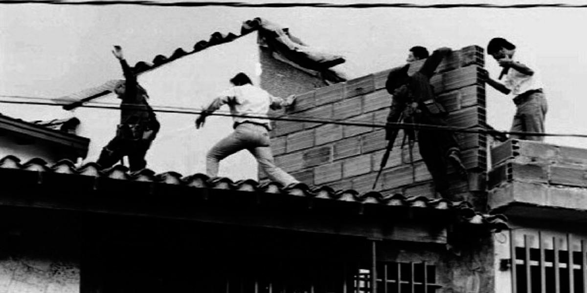 Colombian police and military forces storm the rooftop where drug lord Pablo Escobar was shot dead just moments earlier during an exchange of gunfire between security forces and Escobar and his bodyguard December 2, 1993.