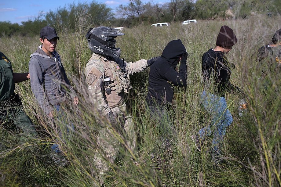 A US Border Patrol agent leads undocumented immigrants after capturing them near the US-Mexico border on December 7, 2015, near Rio Grande City, Texas.