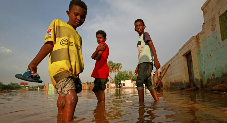 Sudanese boys make their way through a flooded street in the capital's twin city of Omdurman