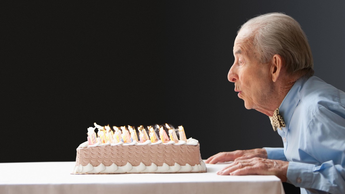 Senior Hispanic man blowing out birthday candles