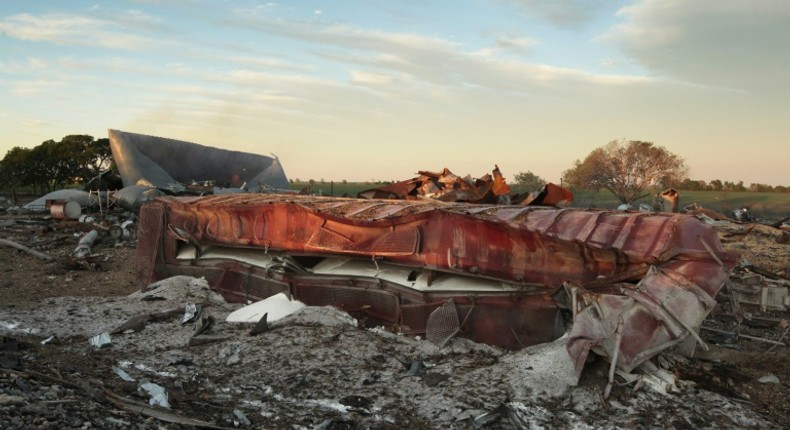 A railroad boxcar filled with ammonium nitrate lays on its side near to the remains of the fertilizer plant that exploded on April 18, 2013 in West, Texas