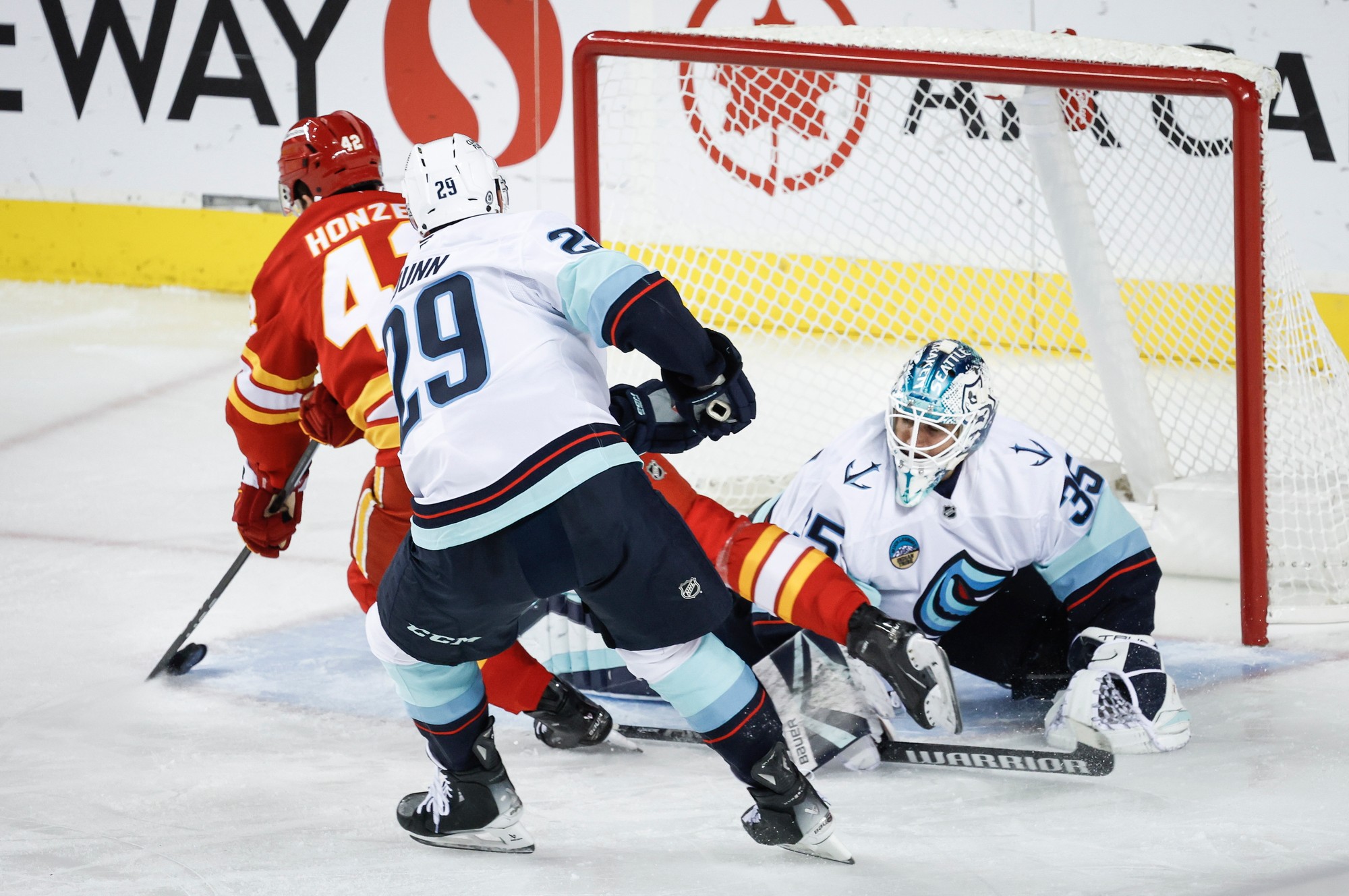 Slovenský hokejista Samuel Honzek (vľavo) z Calgary Flames a brankár Joey Daccord (vpravo) zo Seattlu Kraken.