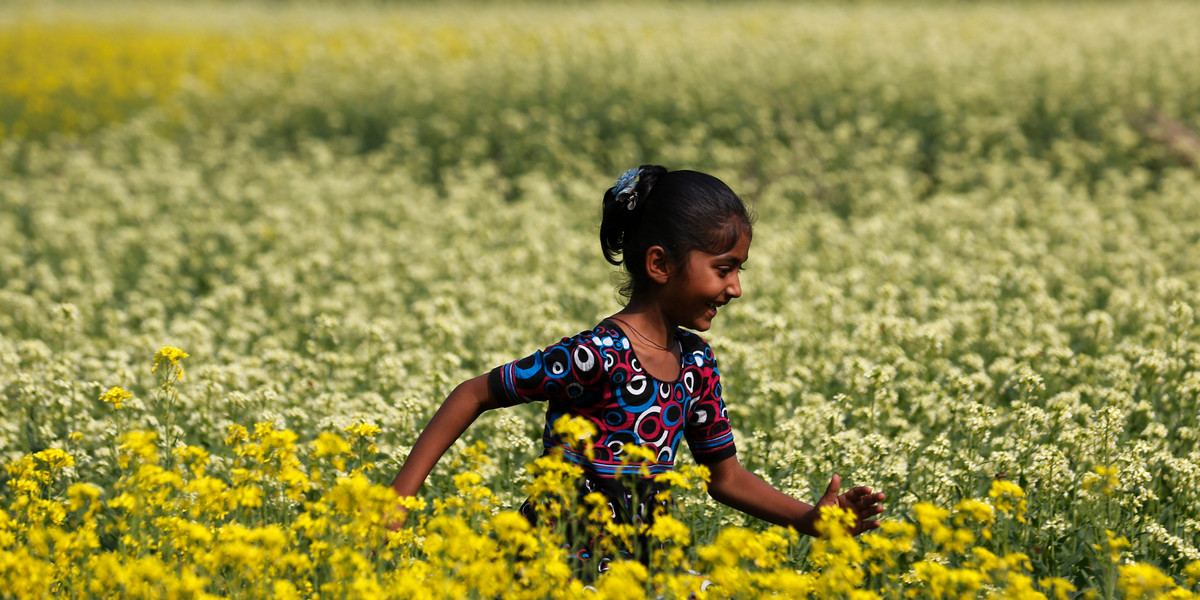 A girl runs through a mustard field on the outskirts of Dhaka, Bangladesh.