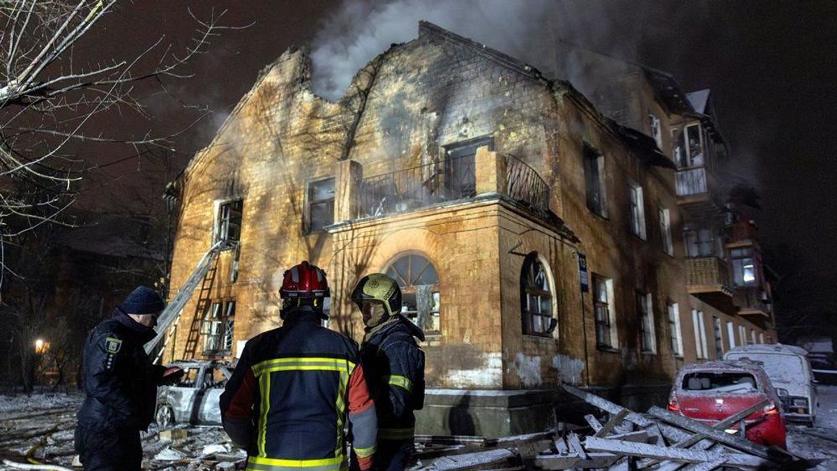 Vatrogasci stoje ispred pogođene zgrade u Kijevskoj oblasti u noći između 8. i 9. januara 2026. | Foto: REUTERS/Thomas Peter