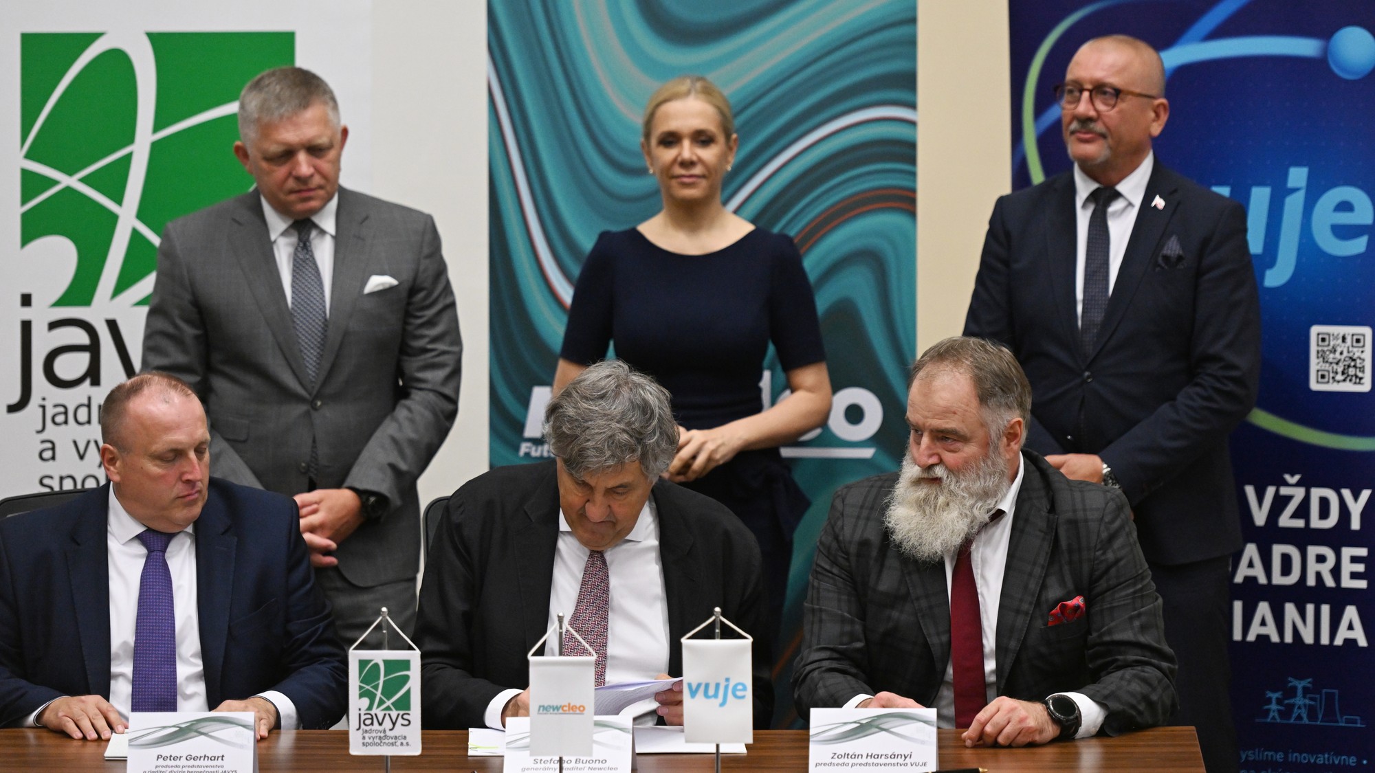 Zľava dole predseda predstavenstva JAVYS Peter Gerhart, generálny riaditeľ Newcleo Stefano Buono a predseda predstavenstva VÚJE Zoltán Harsányi počas podpisu memoranda o spolupráci a v pozadí zľava predseda vlády SR Robert Fico, podpredsedníčka vlády a ministerka hospodárstva SR Denisa Saková a generálny riaditeľ JAVYS Miroslav Obert.