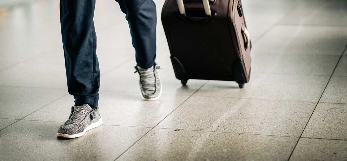Man,With,Luggage,Is,Walking,Along,Airport,Corridor,To,Gate