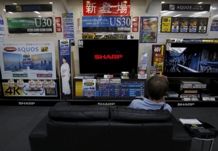 A man sitting on a sofa looks at a Sharp Corp's Aquos TV at an electronics retailer in Tokyo