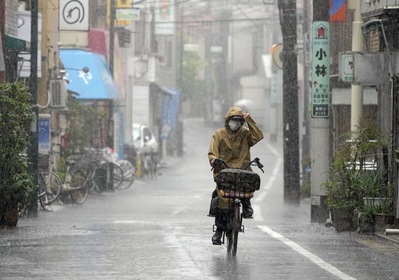 Kobieta jedzie na rowerze podczas ulewnego deszczu w Tokio. Wielki tajfun Nanmadol nawiedził Kiusiu 18 września i powoli przemieszczał się przez Japonię.