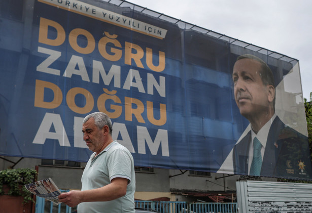 Mężczyzna z gazetą obok billboardu wyborczego obecnego prezydenta Recepa Tayyipa Erdogana