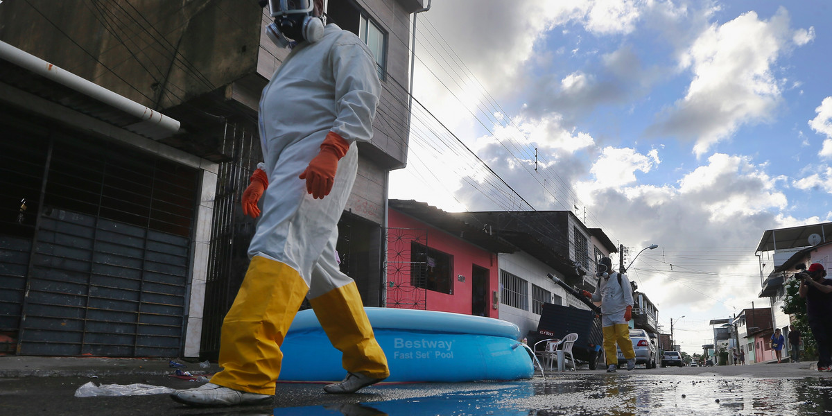 Health workers walk while fumigating in an attempt to eradicate the mosquito which transmits the Zika virus on January 28, 2016 in Recife, Pernambuco state, Brazil