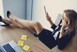 Hot business woman sitting in office with legs on table