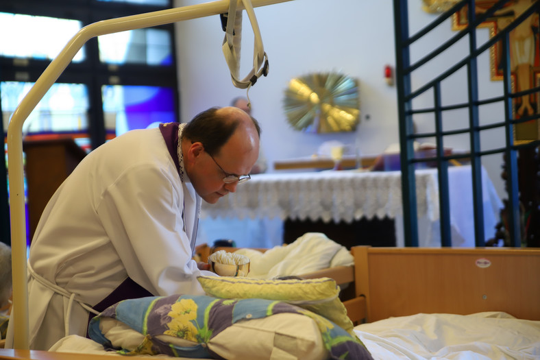 Ks. Adam Trzaska udziela komunii świętej podczas mszy w hospicjum 