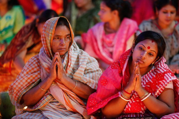 Hindu devotees sit together on the floor of a temple to observe Rakher Upabash for the last day, in 