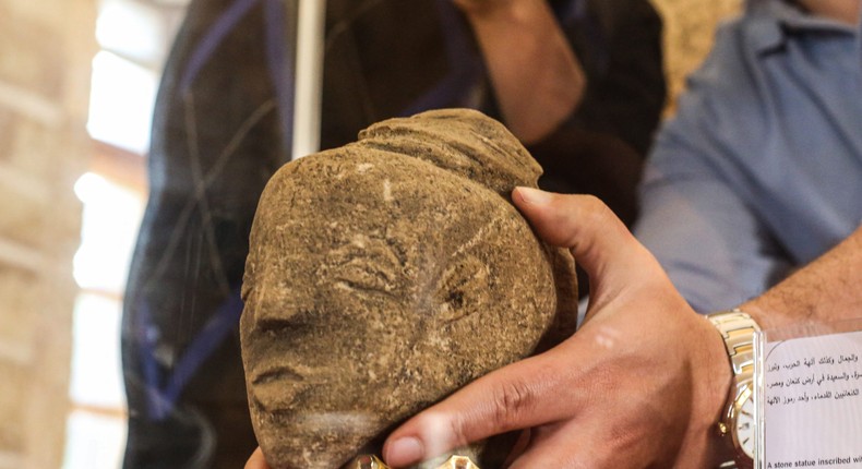 Palestinian archaeologist displays a stone statue carved with the face of Canaanite goddess Anat.