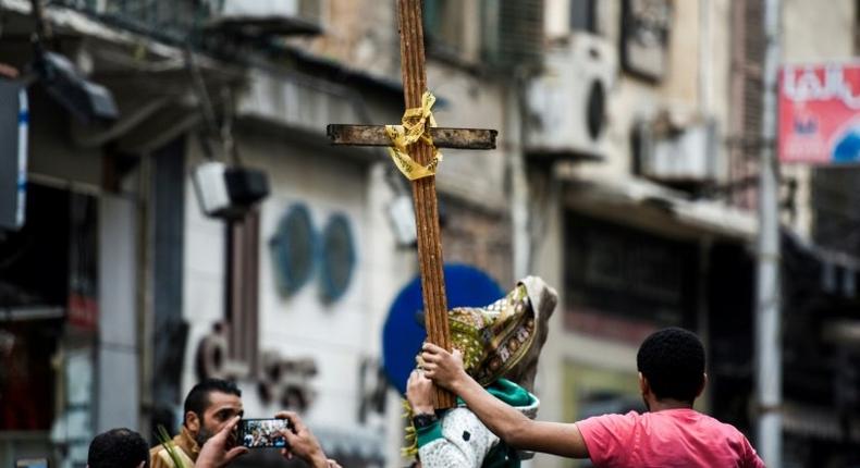Egyptians raise a wooden cross and palm leaves as they gather outside the Coptic Christian patriarchate in the Mediterranean city of Alexandria where a jihadist bombing killed 17 people