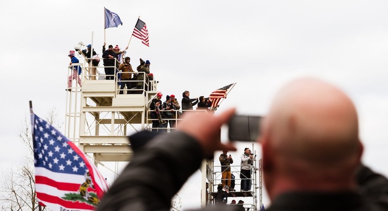 A pro-Trump protester takes a photo of other protesters who climbed a media platform after breaking through barriers onto the grounds of the Capitol Building on January 6, 2021 in Washington, DC.