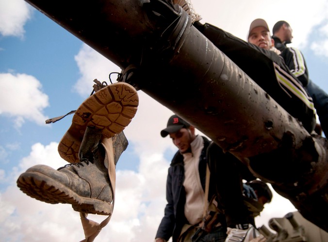 Rebelianci na spalonym czołgu, należącym do sił Muammara Kadafiego, zniszczonym podczas francuskiego nalotu 25 km od Bengazi